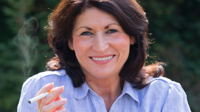 A woman smiling while holding a cigarette